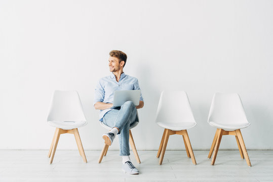 Handsome employee smiling away and using laptop in office - Powered by Adobe