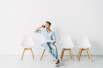 Smiling man talking on smartphone and holding resume in office