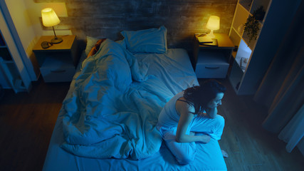 Young woman suffering from insomnia while her husband is sleeping. Room with moon light.