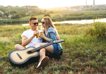 Couple in love with sunglasses drinking beer and enjoying the sunset.