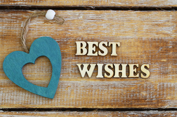 Best wishes written with wooden letters on rustic surface and a wooden heart
