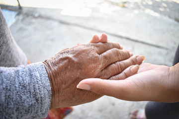 Hands of two people represent family warmth and care for the elderly.