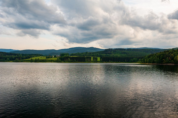 Sunset at the lake. Evening at pond with cloudy stormy sky. Sumava, Bohemian Forest, Böhmerwald, Czech Republic.