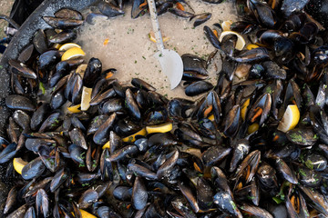 Fresh mussels in shells at steam pan. Seafood barbecue outdoors.