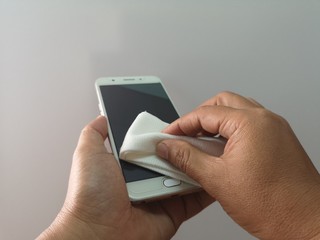 Women currently using a cleaning cloth to clean mobile phone, to prevent dust
