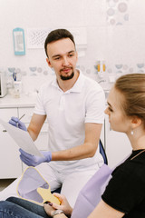 Obraz premium A beautiful girl sits in the dentist's chair and listens to the doctor. Dentist appointment and dental health care