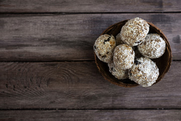Useful snack for vegans, protein bars or energy balls on a wooden background in a coconut scarlet, delicious homemade sweets, healthy ingredients