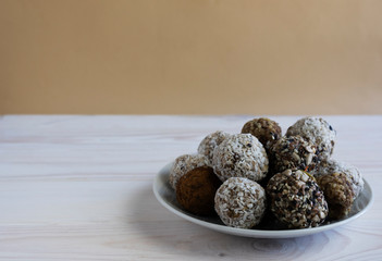 Close-up on a white plate of healthy energy balls in coconut, cocoa and cinnamon, healthy snack, horizontal orientation