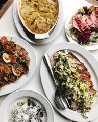 Delicious flatlay of lunch in a restaurant featuring slow roasted pork belly, potato gratin, seafood platter and salad