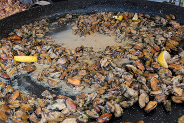 Fresh mussels seafood mix cooking steaming in large wok pan during hotel brunch