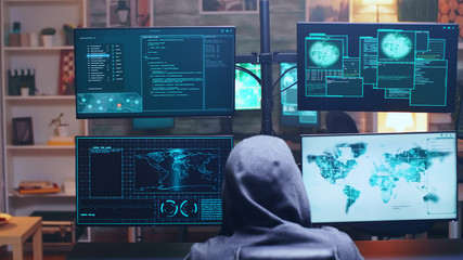 Back view of cyber terrorist using supercomputer to hack government firewall.