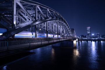 Fototapeta na wymiar ICE Zug fährt nachts über die Hohenzollernbrücke in Köln ein