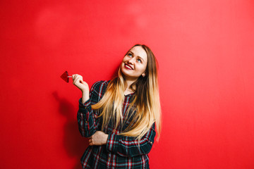 Beautiful brunette girl with a candy in her hand having fun on a red background.