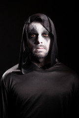Fototapeta na wymiar Grim reaper with a hood isolated over black background. Halloween costume.