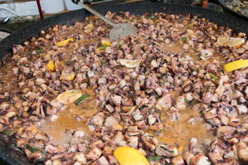 Boiled and seasoned with spices chopped pieces of octopus bites, cooking in a large wok