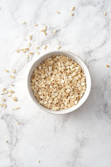 Oat flakes in bowl on white background. Copy space.