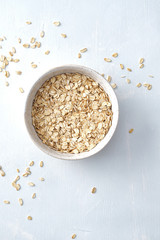 Oat flakes in bowl on white background. Copy space.