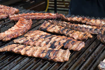 Chef cooking fresh pork ribs on the charcoal grill, during food festival, street food