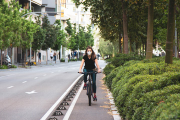 Chica joven de ojos claros, yendo en bicicleta durante coronavirus en una ciudad.