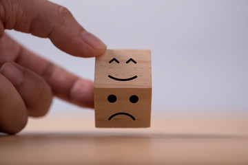 Hand flipping change emotions from sad to happy which print screen on wooden cubic. Customer...