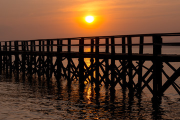Obraz premium Sunset over the sea and a black wooden pier