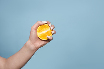 half oranges in hands on blue background, citrus objects