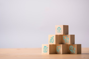 Wooden cubes stacking of healthcare medicine and hospital icon on table. Health care insurance business and investment.
