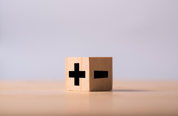 Black of plus and minus sign in opposite side of wooden cube.