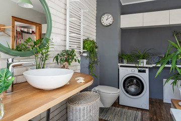 Modern interior of bathroom with green plants and natural jungle at home. Wooden counter with...