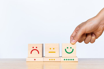 Customer hand showing a feedback with smile face wood cube. Service rating, satisfaction concept