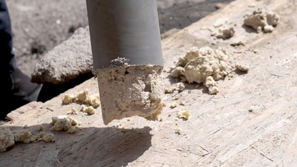 A plumber removes solid deposits from grease and debris from a plastic sewer pipe.