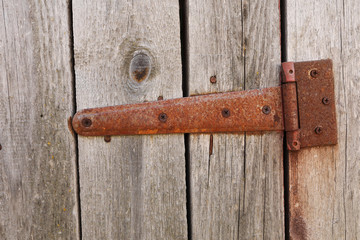 rusted forged curtain on a wooden door. Part old wooden door. Barn. Cracked. The door to the hinges. Close Up of wood.