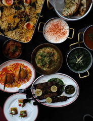 Indian food feast in a restaurant featuring burgers, rice, curry, lamb skewers, bbq meats and breads
