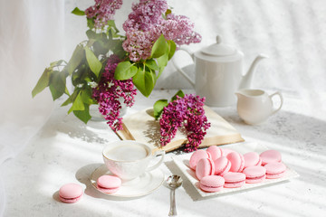 A Cup of morning coffee, a bowl of lilac, macaroni, on a light background. Postcard good morning