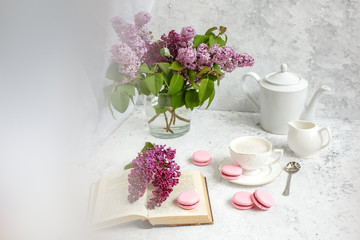 A Cup of morning coffee, a bowl of lilac, macaroni, on a light background. Postcard good morning