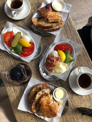 Delicious homemade breakfast in the garden on a sunny day with coffee, eggs, bread, ham, salmon, tomatoes and avocado