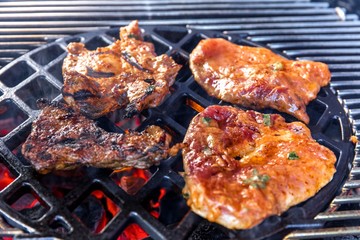Grilling marinated meat on a charcoal grill. Grilled steak on the grill, close-up. Summer garden party.