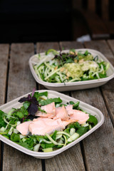 Delicious fresh salmon and greens salad in a take away box ready for delivery