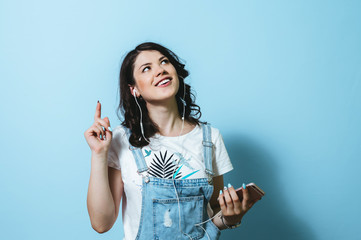 Portrait of happy woman wearing earphones singing isolated over blue background