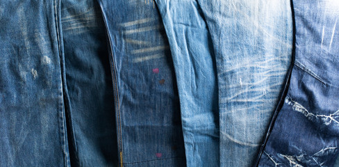 Stack of various shades blue jeans. Jeans stacked isolated on white background. Blue denim jeans texture banner with copy space for text design background. Canvas denim fashion texture