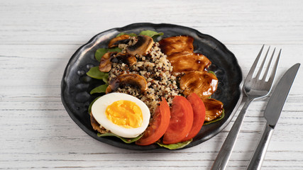 Healthy quinoa salad with spinach tomato egg chicken breast and mushrooms in teriyaki sauce and sesame seeds