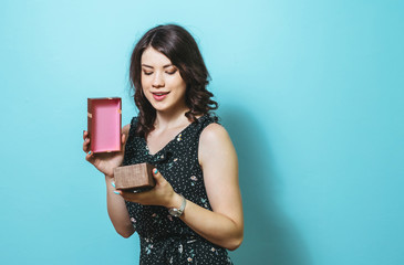 Portrait of a happy smiling girl opening a gift box isolated  over blue background