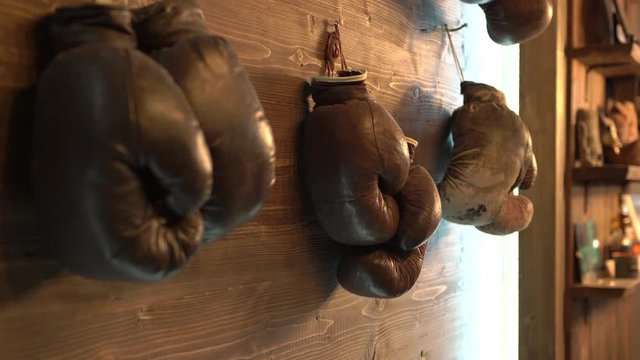 Fight club, sports hall. A wooden wall with brown leather, old frayed boxing gloves hung nails. Retro style. Stylish sports hall. Active fighting sports health self-defense. Useful hobby hobby in life