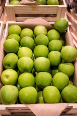 Pile of fresh green apples in wooden crate box for sales in a local market or supermarket