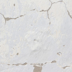 the background of the cracked white wall of the house is old covered with plaster and the paint is peeling from time. Very old house. cracks in the wall