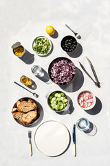 Photo of a fresh spring salad on a white porcelain plate and vegetable mix of ingredients in metal bowl on a white rustic background sunlight with shadows
