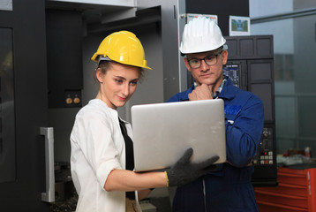 Male and Female Industrial Engineers in Hard Hats Discuss New Project while Using Laptop. They Work in a Heavy Industry Manufacturing Factory.