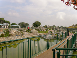 Bridge over an artificial canal with a miniature ship and small houses and rocks around