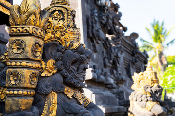 Fototapeta na wymiar Balinese stone statue against the blue sky and trees