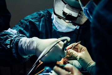 Close up doctor with surgical tools making surgery in the operating room, baldness treatment, hair transplant
